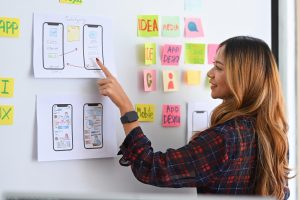 young female designer planning mobile app development prototype wireframe design whiteboard